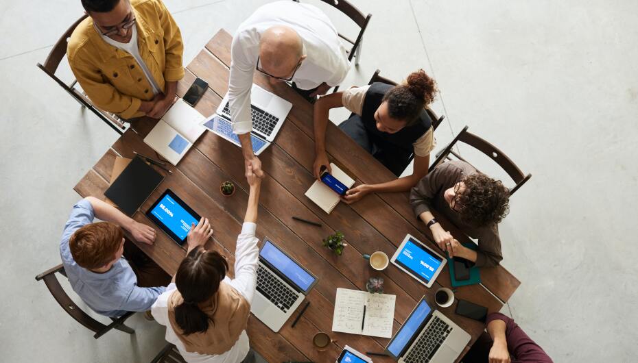 Adults at table with computers shaking hands