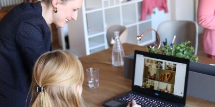 two girls at a computer smiling