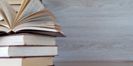 Stack of books on the left of a table with a wooden background