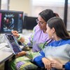 two female students looking at a sketch on a tablet in a computer lab
