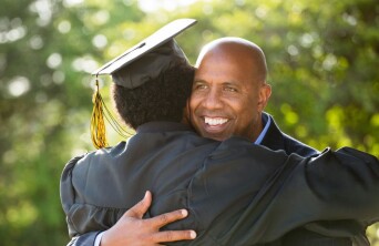 Male parent hugging his son at graduation.