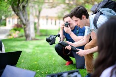 two male students taking photos of other students outdoors