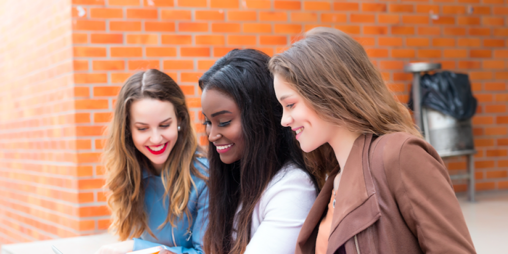 three girls sitting outside campus