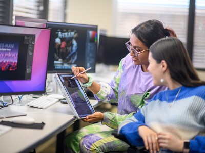 two female students looking at a sketch on a tablet in a computer lab